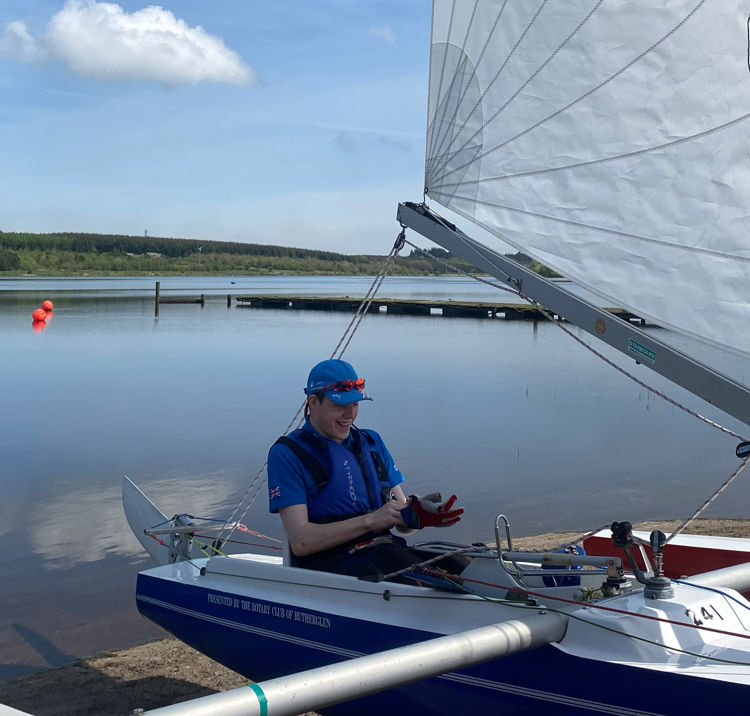 Mid shot of young sailor sat in sailboat smiling