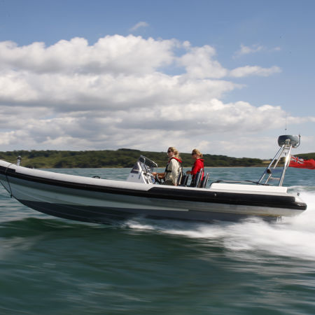 Side view of powerboat speeding across the ocean with numerous people onboard