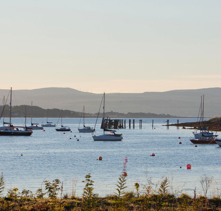 Very long shot of distant boats in water as sun is setting