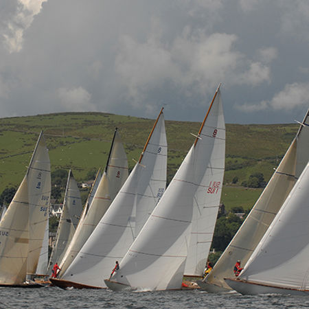 Long shot of fleet of sailboats in a line
